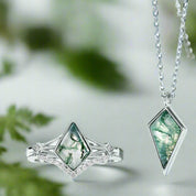 Jewelry set with a ring and pendant featuring green gemstones on a light blue background
