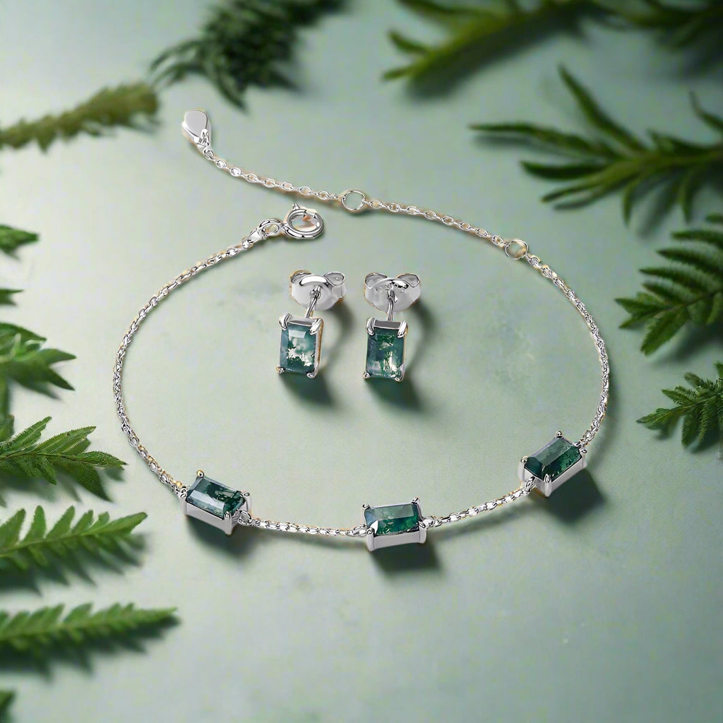 Jewelry set with bracelet and earrings featuring green gemstones on a white background.