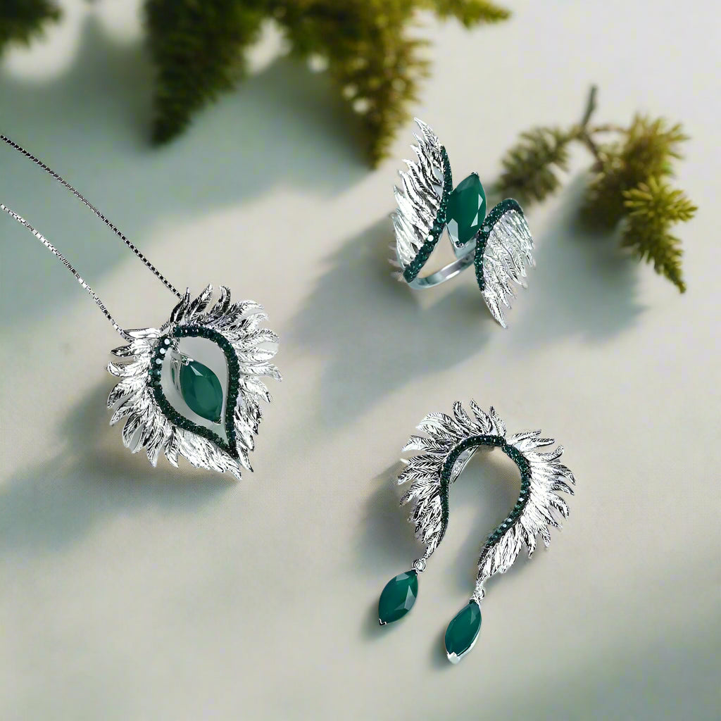 Jewelry set with silver and green earrings and ring on a light blue background