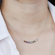 Necklace with colorful stones worn by a person in a white shirt