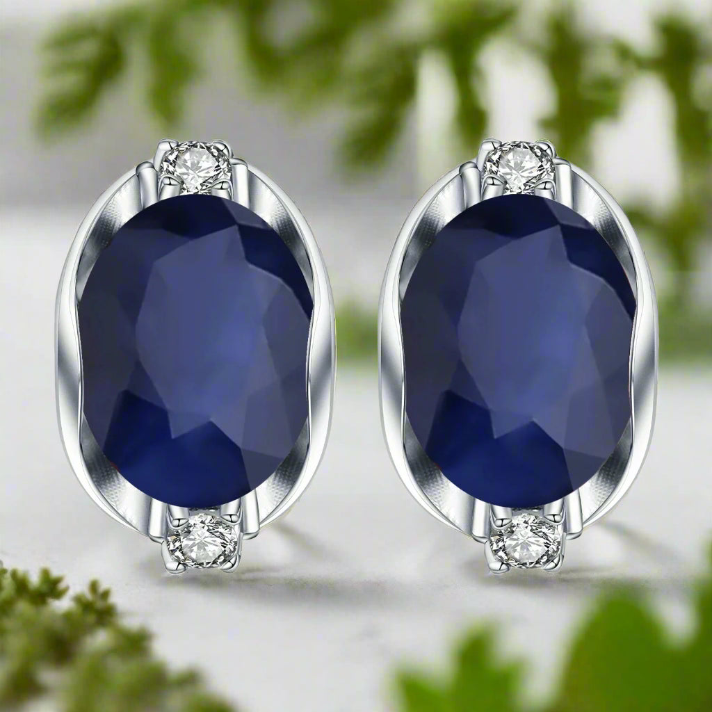 Pair of earrings with blue gemstones and silver settings on a white background
