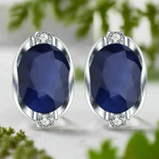 Pair of earrings with blue gemstones and silver settings on a white background