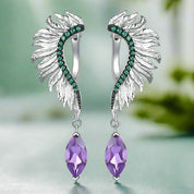 Pair of earrings with feather-like design and purple gemstones on a white background