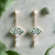 Pair of earrings with green fan design and pearl tops on a white background