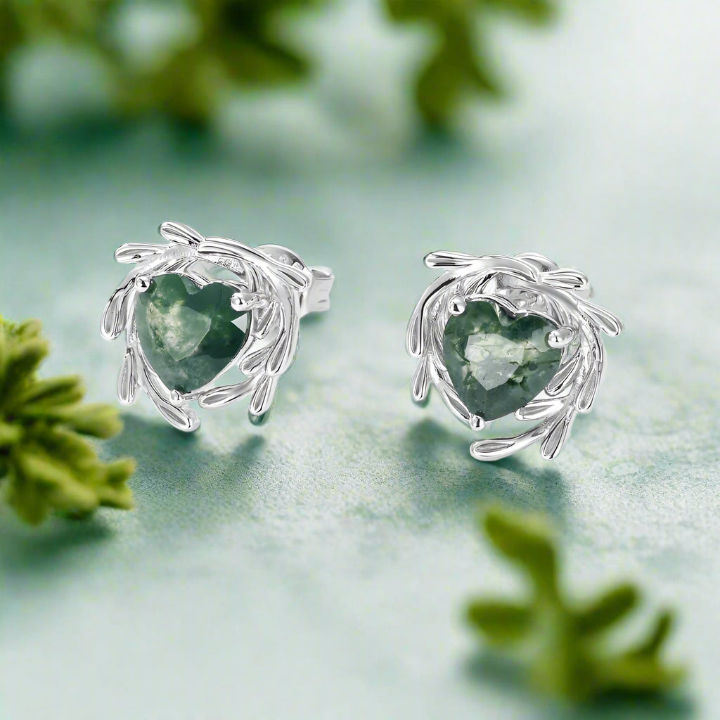 Pair of silver earrings with green heart-shaped stones on a white background