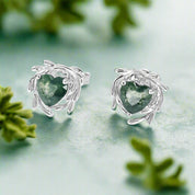 Pair of silver earrings with green heart-shaped stones on a white background