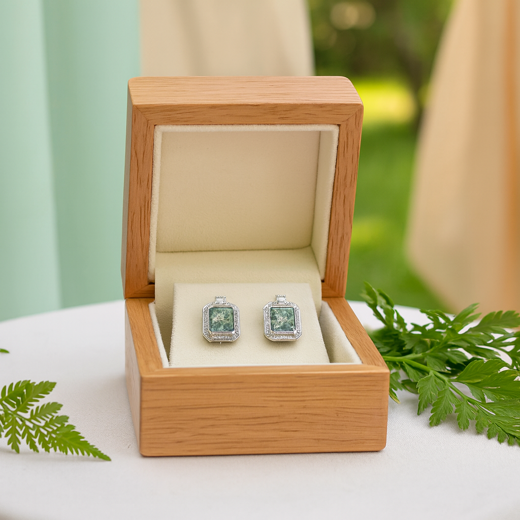 Pair of square green gemstone earrings in a wooden box with a natural background