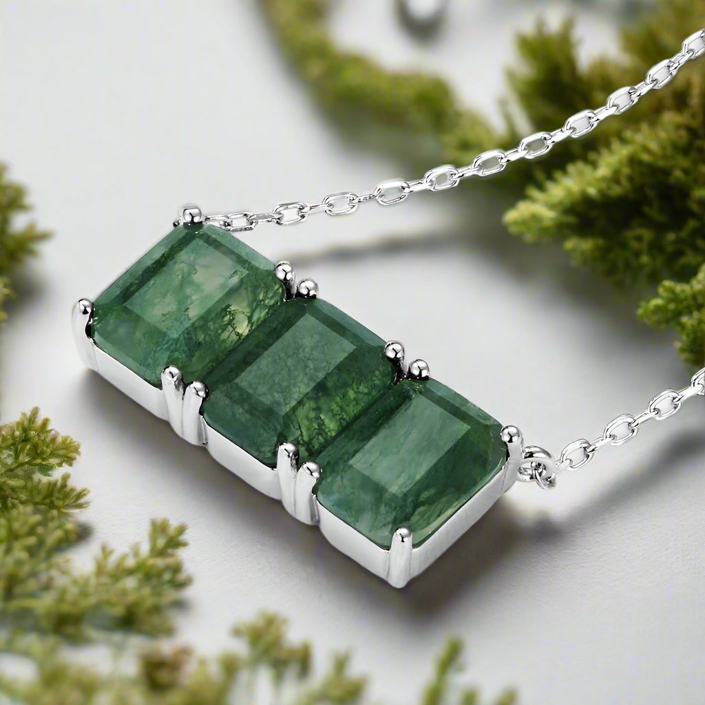 Green gemstone necklace with silver chain on a white background