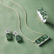 Jewelry set with emerald green stones on a green background