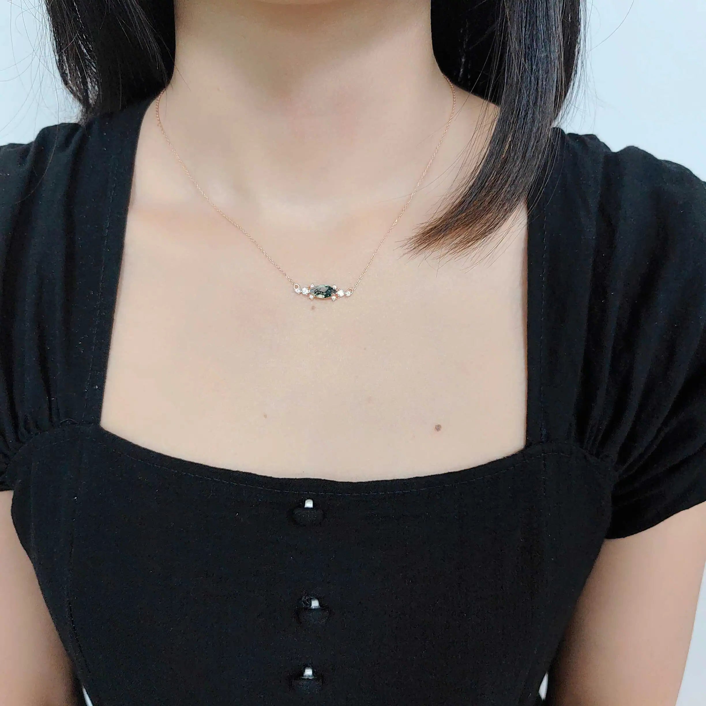 Person wearing a delicate necklace with a plain background