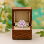 Pink gemstone ring in a wooden box with a floral background