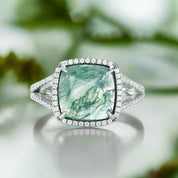 Ring with a green gemstone and diamond accents on a light blue background