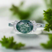 Ring with a green gemstone and silver accents on a light blue background