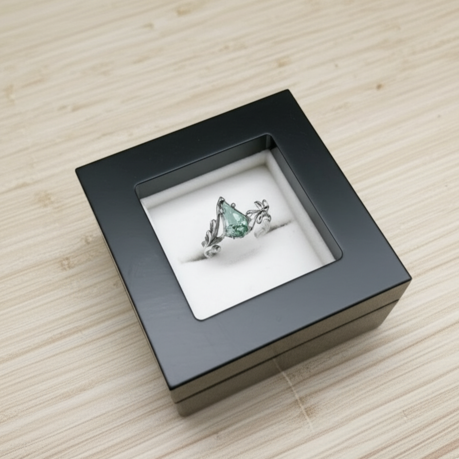 Ring with a green gemstone in a black box on a wooden surface