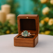 Ring with a green gemstone in a wooden box on a blurred natural background