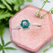 Ring with a green gemstone on a pink fabric background