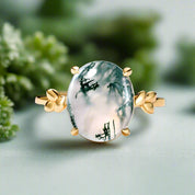 Ring with a green stone and gold accents on a light blue background