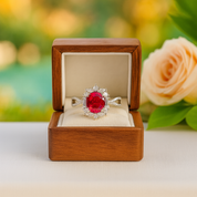 Ring with a red gemstone in a wooden box with a blurred floral background
