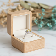 Ring with a yellow gemstone in a wooden box on a light surface with decorative elements.