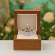 Ring with green gemstone in a wooden box against a blurred floral background
