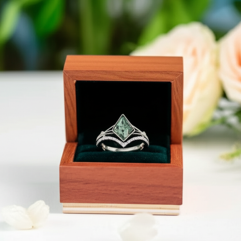 Ring with green gemstone in a wooden box on a blurred floral background