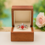 Ring with red gemstone in a wooden box against a blurred floral background