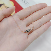 Rose gold necklace with a pendant held in a hand against a blurred background