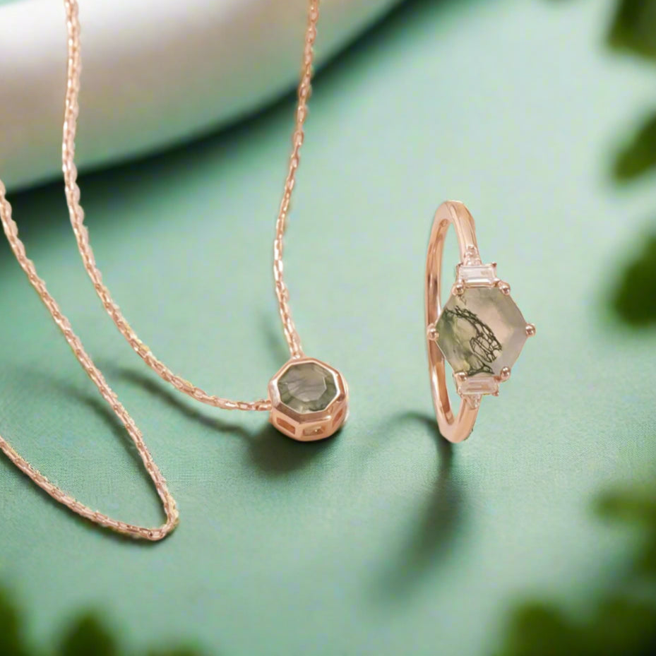 Rose gold necklace with green gemstones on a beige surface