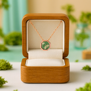Rose gold necklace with green pendant in an open wooden jewelry box on a blurred natural background