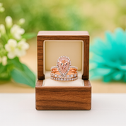 Rose gold ring set in a wooden box with a blurred floral background