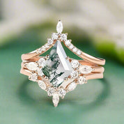 Rose gold ring with a central green gemstone and diamond accents on a light background