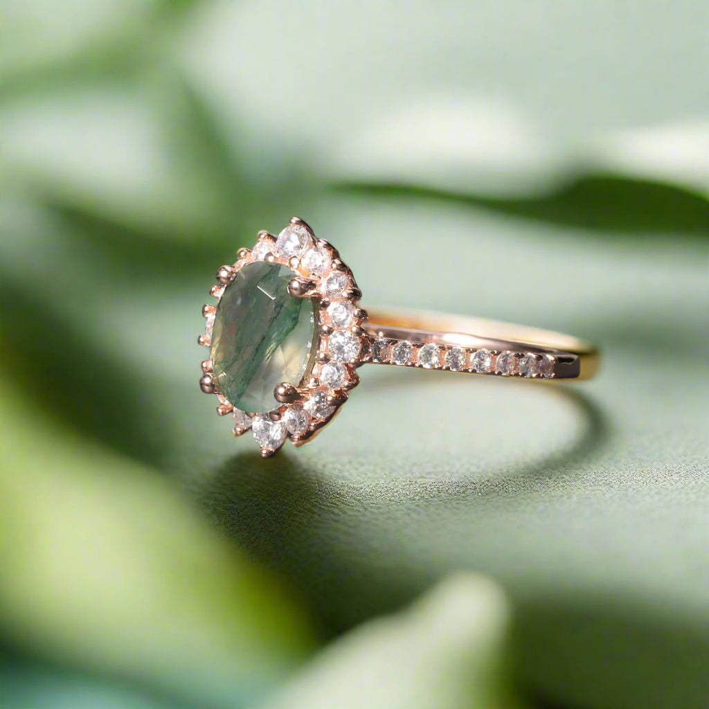Rose gold ring with a green gemstone and diamonds on a dark surface