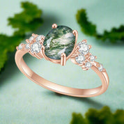 Rose gold ring with a green gemstone and small diamonds on a white background