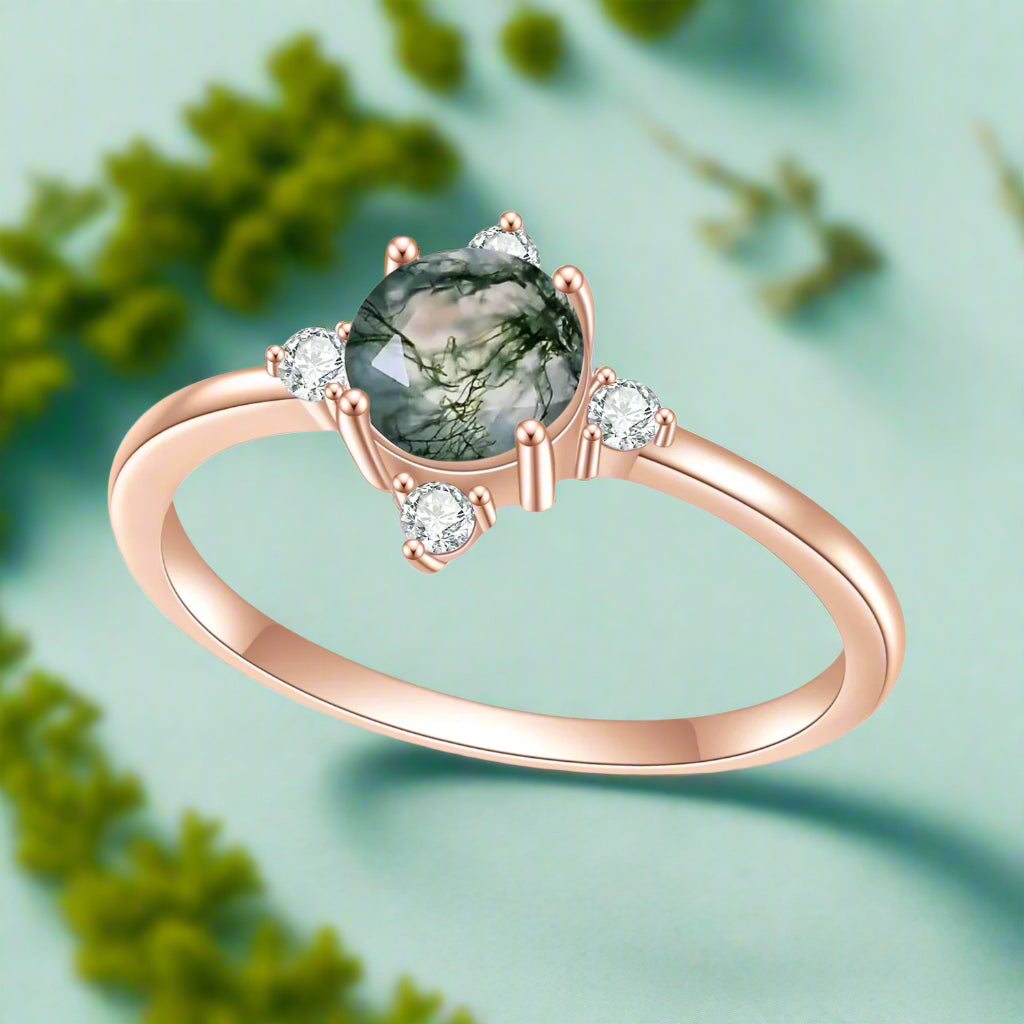 Rose gold ring with a green gemstone and small diamonds on a white background