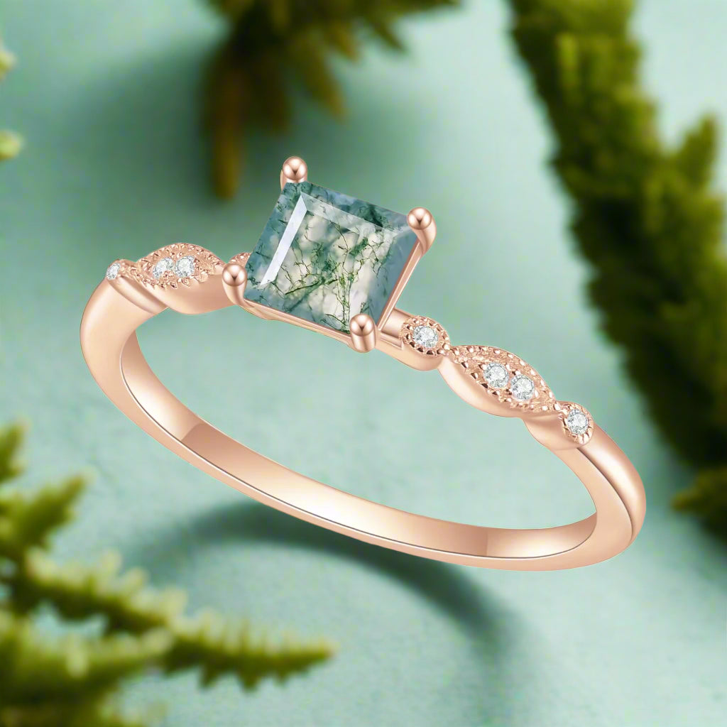 Rose gold ring with a green gemstone and small diamonds on a white background
