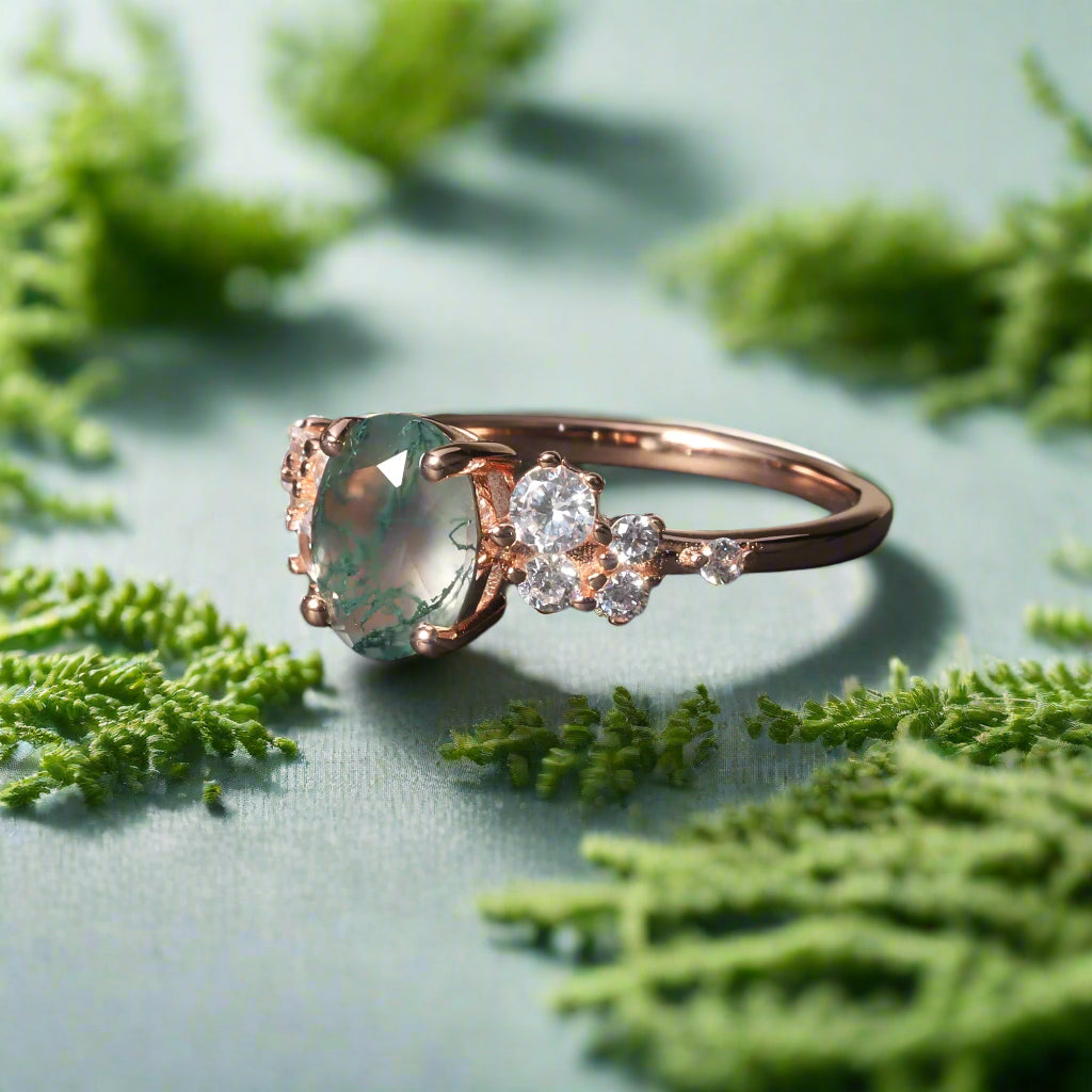 Rose gold ring with a green gemstone and smaller diamonds on a dark background