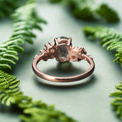 Rose gold ring with a green gemstone on a dark surface