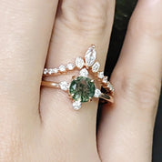 Rose gold ring with a green gemstone on a person's finger against a blurred background