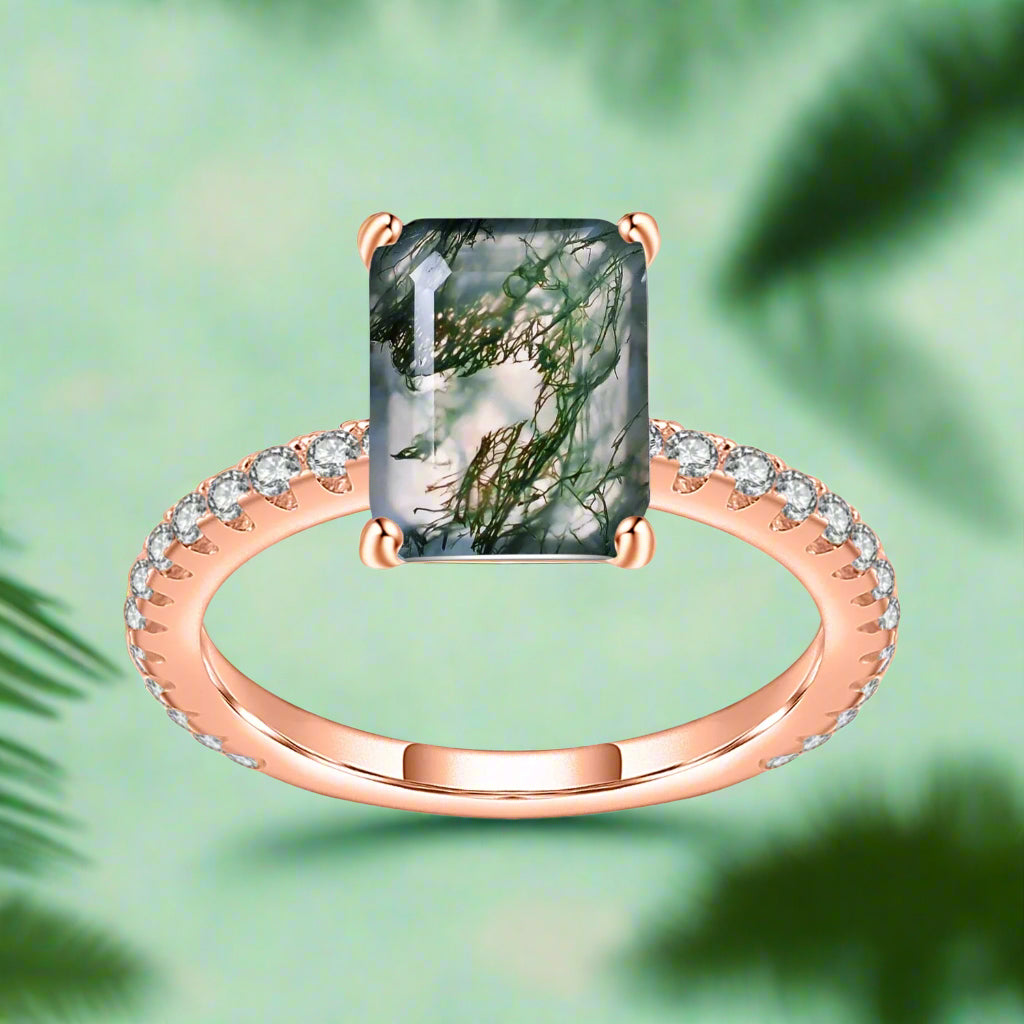 Rose gold ring with a large green gemstone and smaller diamonds on a white background