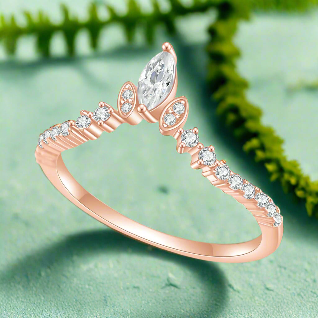 Rose gold ring with a pear-shaped diamond and smaller diamonds on a white background