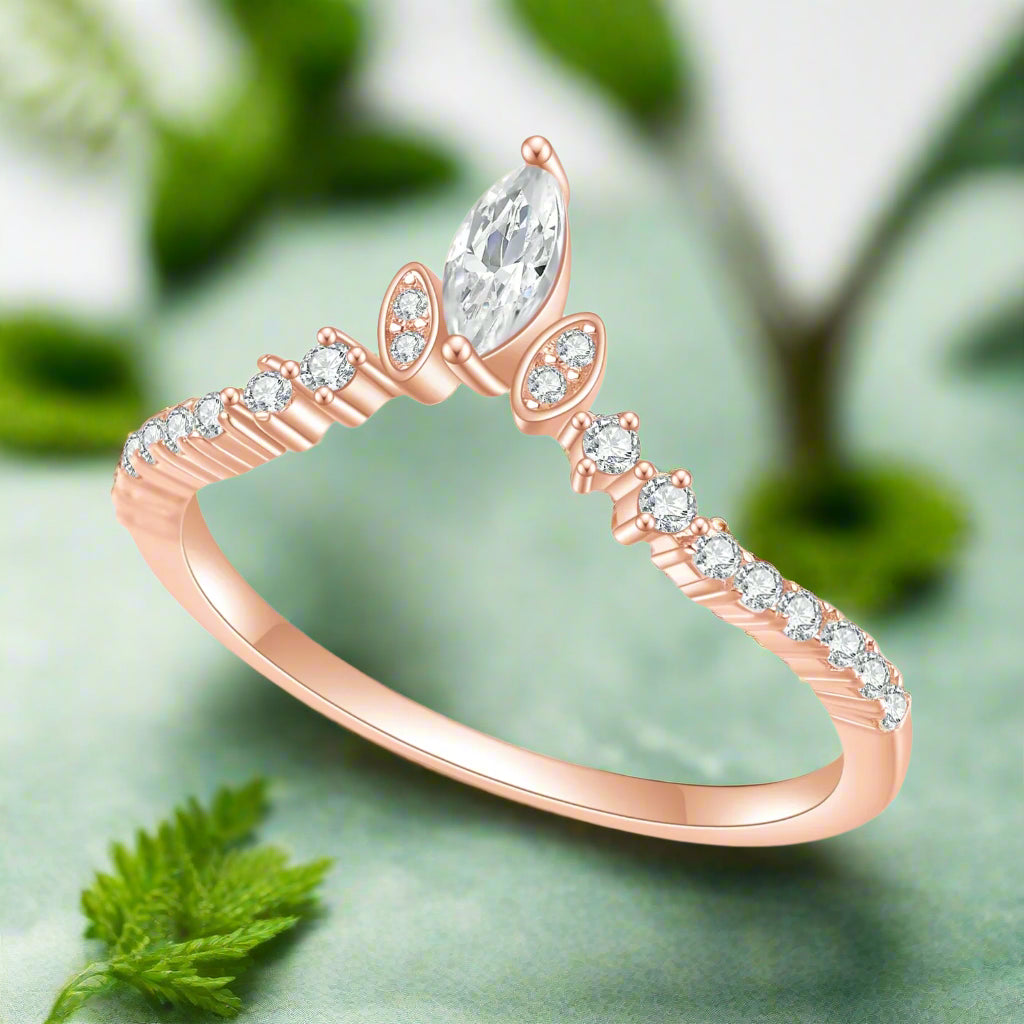 Rose gold ring with a pear-shaped diamond and smaller diamonds on a white background