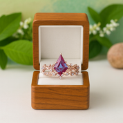 Rose gold ring with a purple gemstone in an open wooden box against a natural background