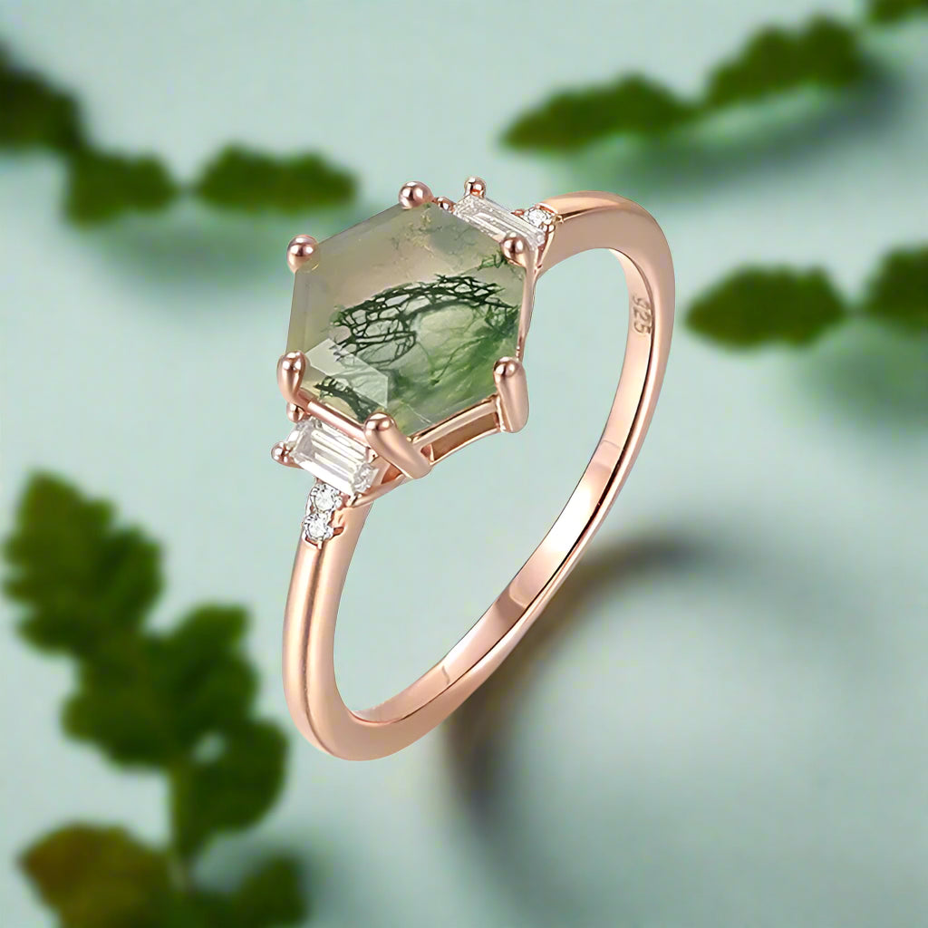 Rose gold ring with green gemstone and diamonds on a white background