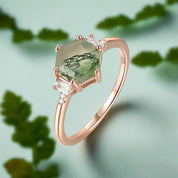 Rose gold ring with green gemstone and diamonds on a white background