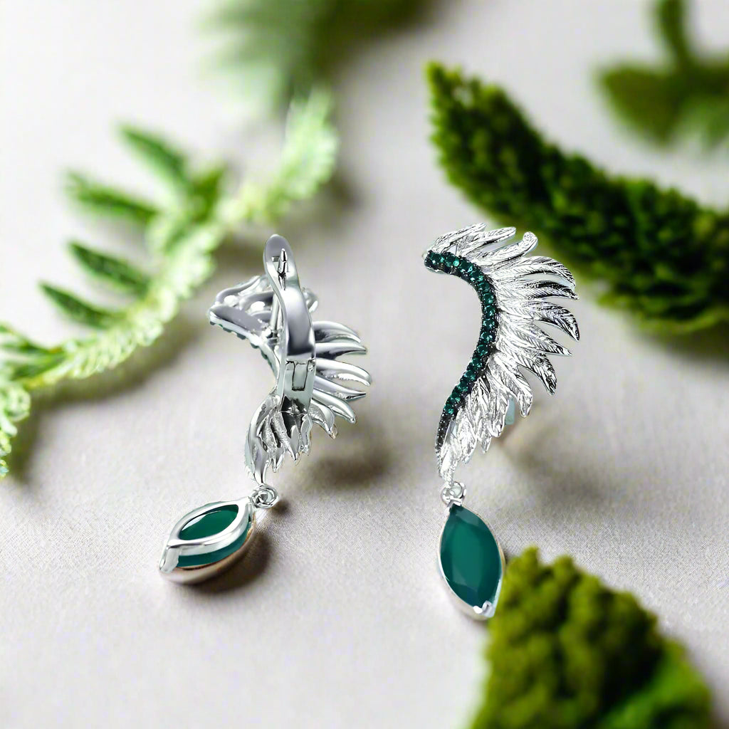Silver earrings with green gemstones on a light blue background
