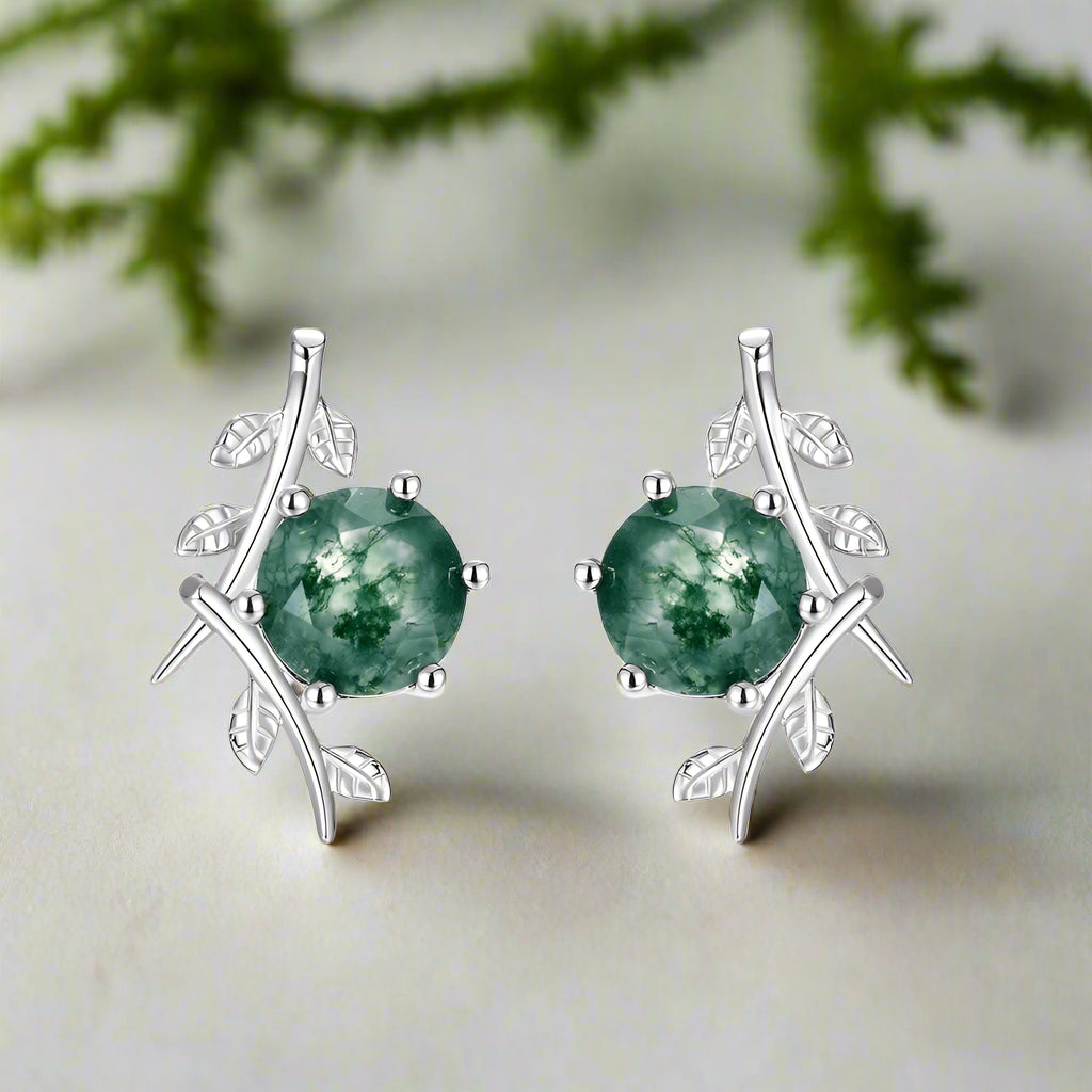 Silver earrings with green gemstones on a white background