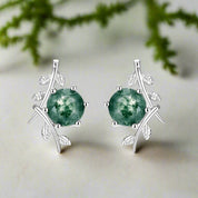 Silver earrings with green gemstones on a white background