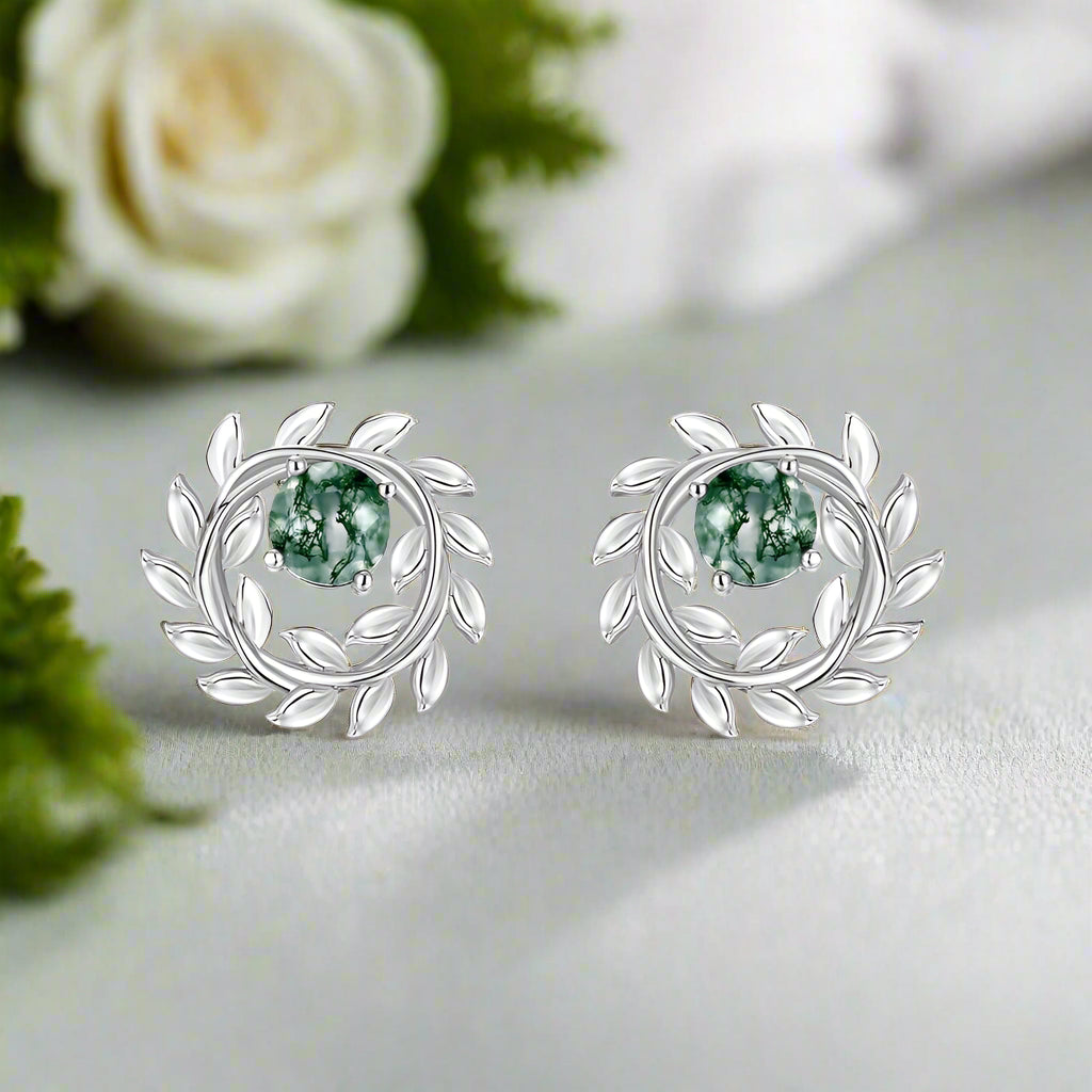 Silver earrings with green gemstones on a white background