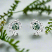 Silver earrings with green gemstones on a white background