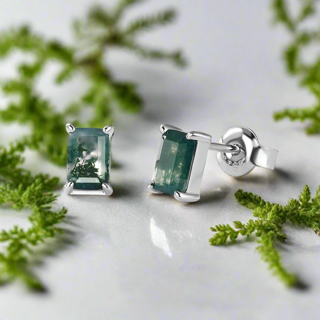 Silver earrings with green gemstones on a white background